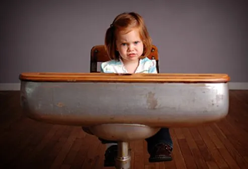 Una niña no está contenta de tener que permanecer sentada durante la clase.