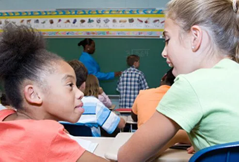 Una niña habla excesivamente a otra niña mientras está en clase.